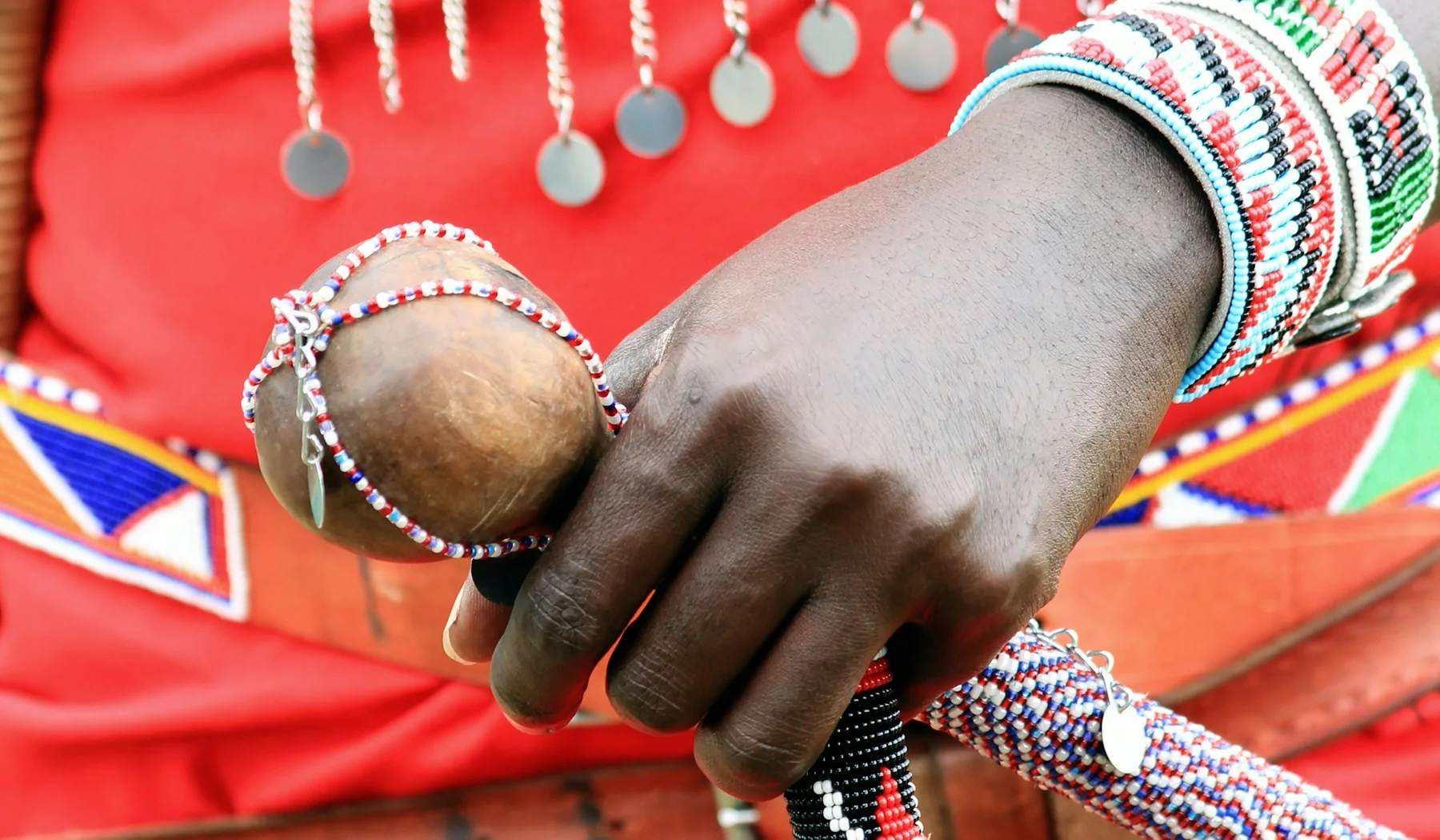 Close view of Maasai beadwork, red cloth and a beaded speaking stick