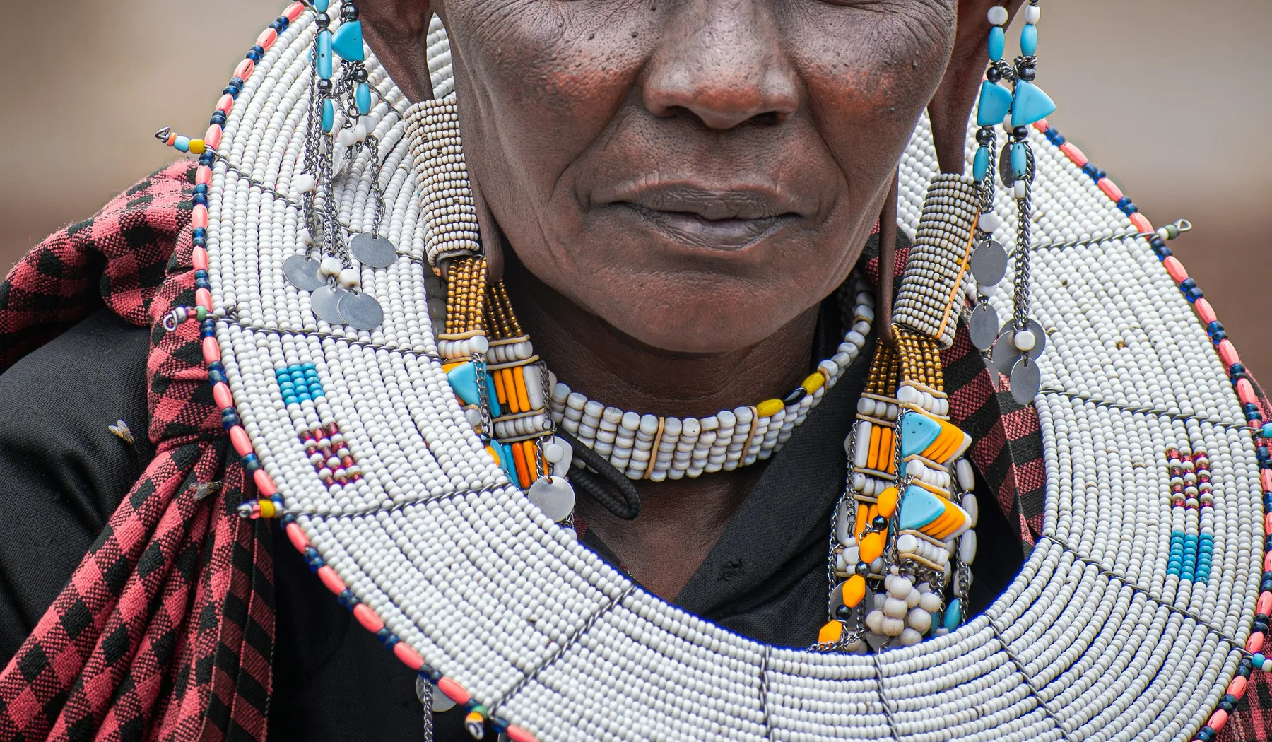 Maasai woman wearing detailed white, turquoise and orange beadwork