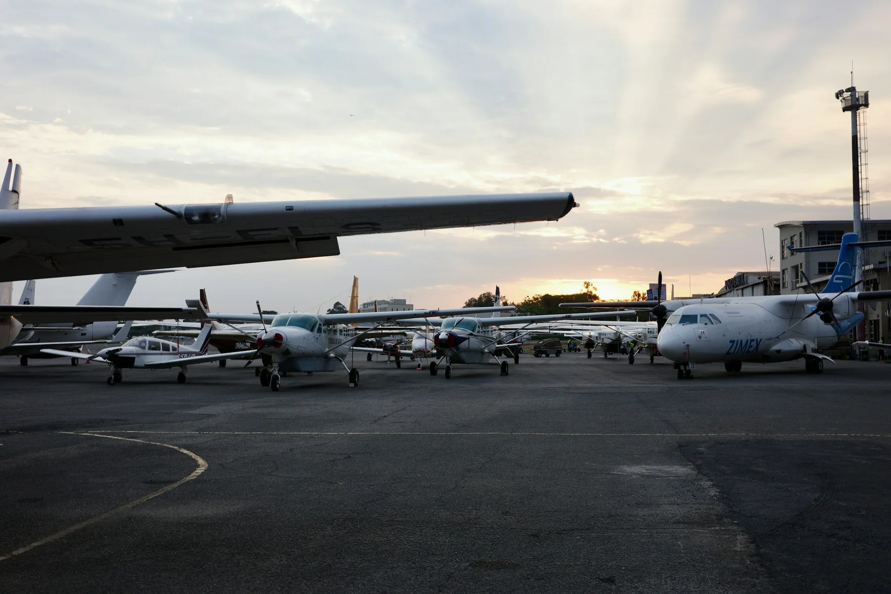 Several small propeller aircraft parked on the Wilson Airport tarmac at sunset
