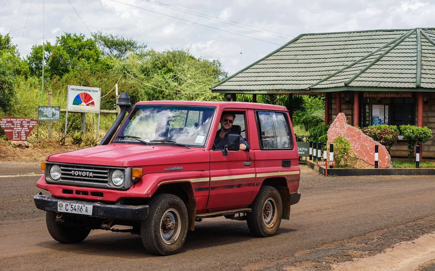 Red four-wheel-drive vehicle at the entrance to Meru National Park