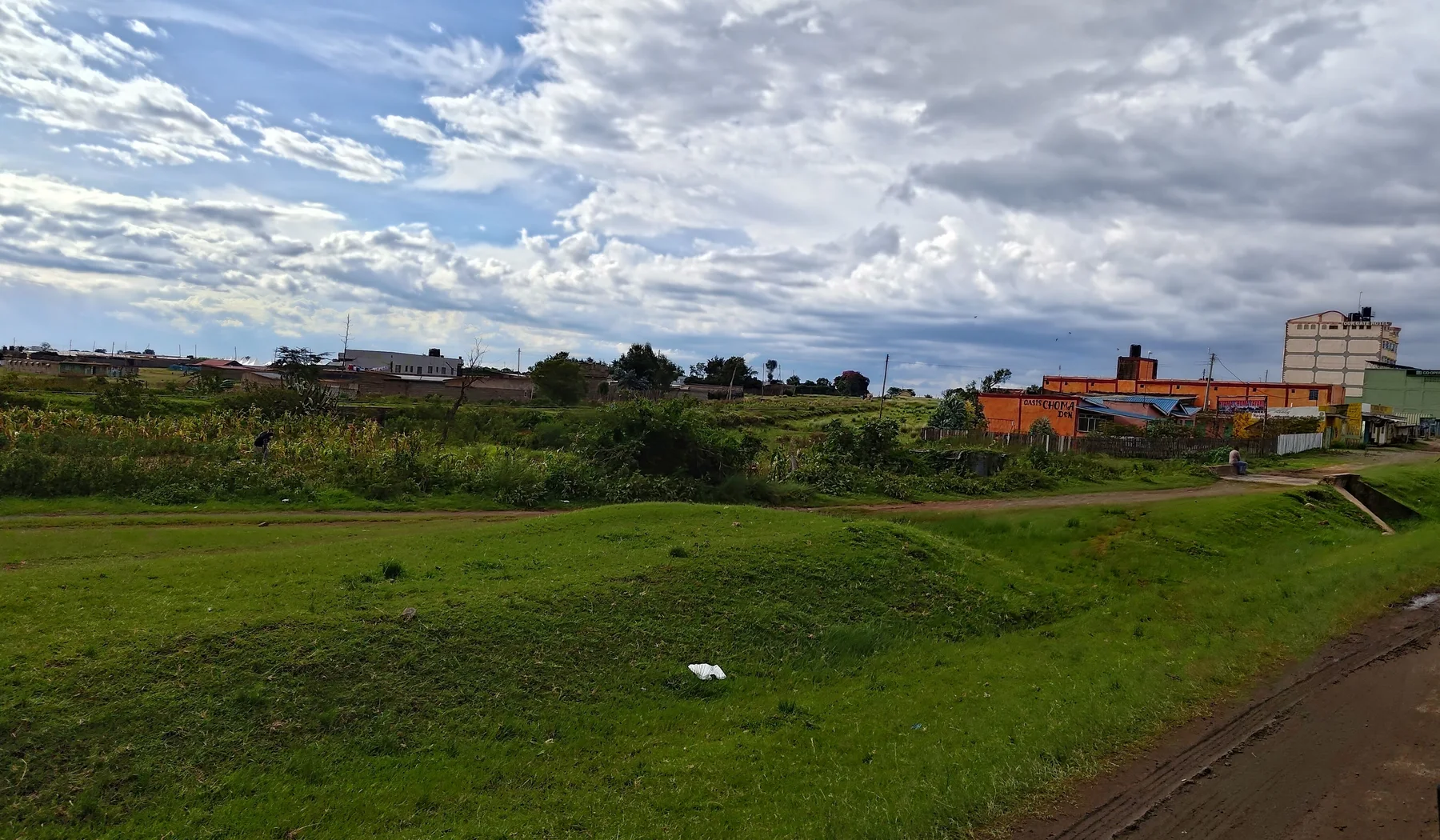 Green fields and buildings under a wide clouded sky in Naro Moru, Kenya