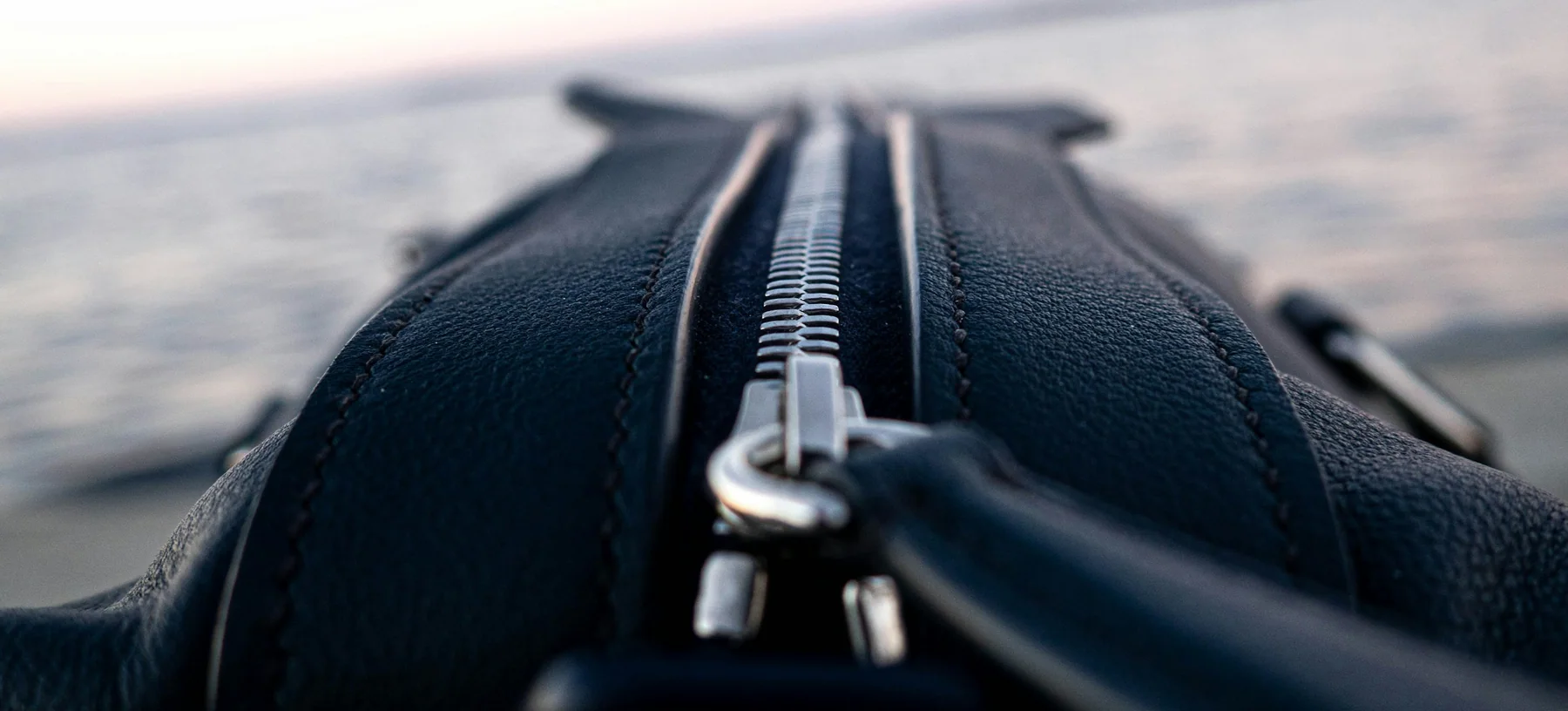 Close view of the zipper and soft sides of a black travel duffel bag