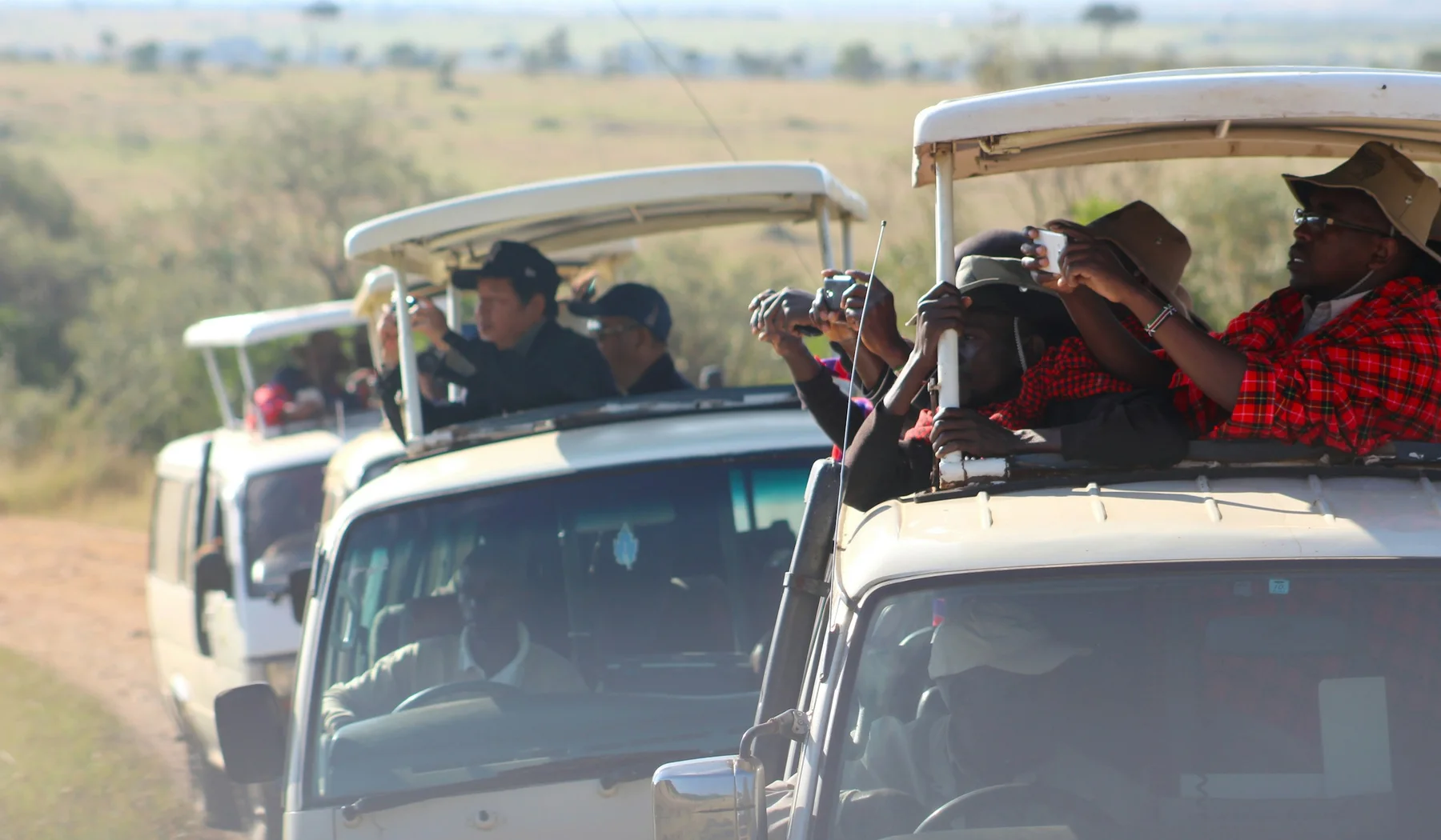 Travellers photographing wildlife from a safari vehicle in the Maasai Mara