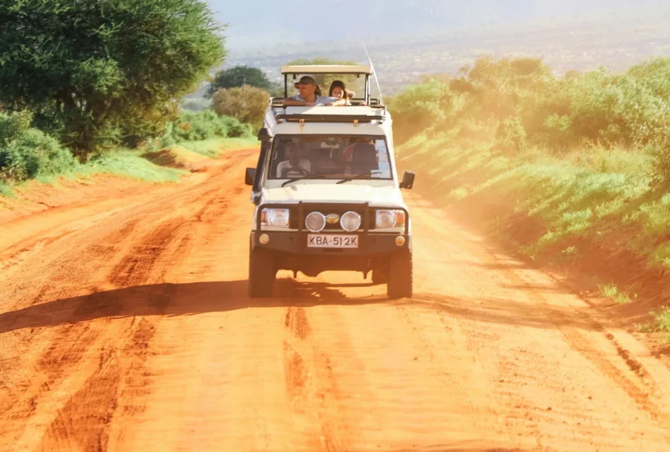Safari vehicle travelling along a dirt road in Kenya