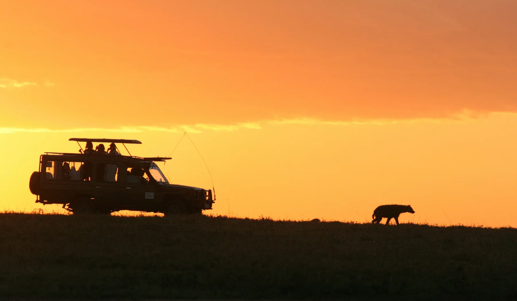 Safari vehicle silhouetted against the evening sky in Kenya