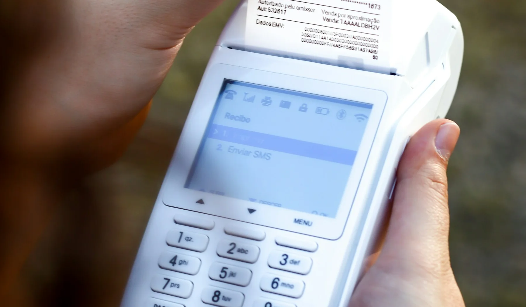 A person compares a payment receipt with the information on a phone